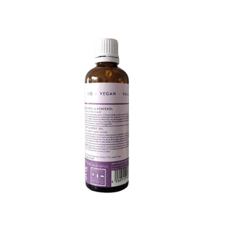An amber glass bottle of body and hair oil with a white cap, shown from the back with a white label featuring purple text and a barcode.
