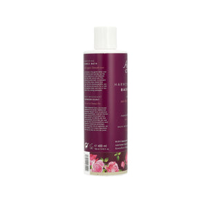 A bottle of Rosemary & Rosebody Harmonic Balm shown from the back, featuring a deep burgundy label with white text and pink rose illustrations at the bottom, topped with a white cap.